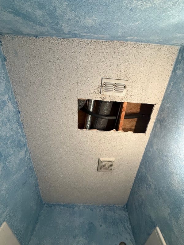 Bathroom ceiling opened up, ducting and joists visible above the vent