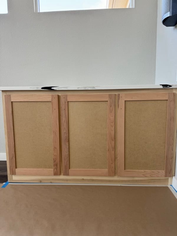 Base cabinet in bare unfinished wood with raw panel fronts before painting