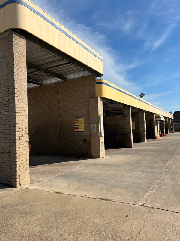 Self-serve car wash in bare tan brick with dated cream and blue trim