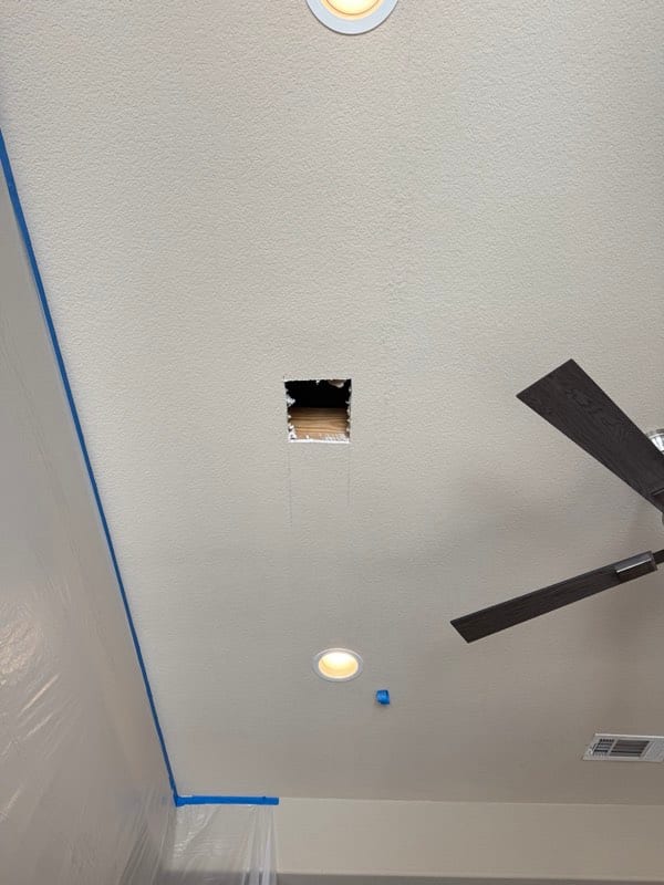 Square hole cut in a textured ceiling, room masked off below