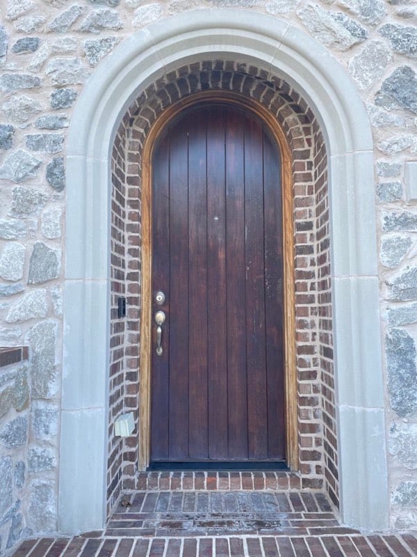 Arched wooden front door with a faded, weather-worn finish