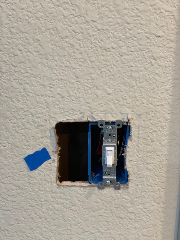 Drywall broken open around a light switch box