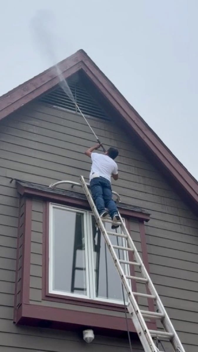 Patch Plus Paint soft washing siding and trim from a ladder