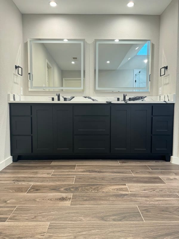 The finished vanity painted black beneath the lit mirrors