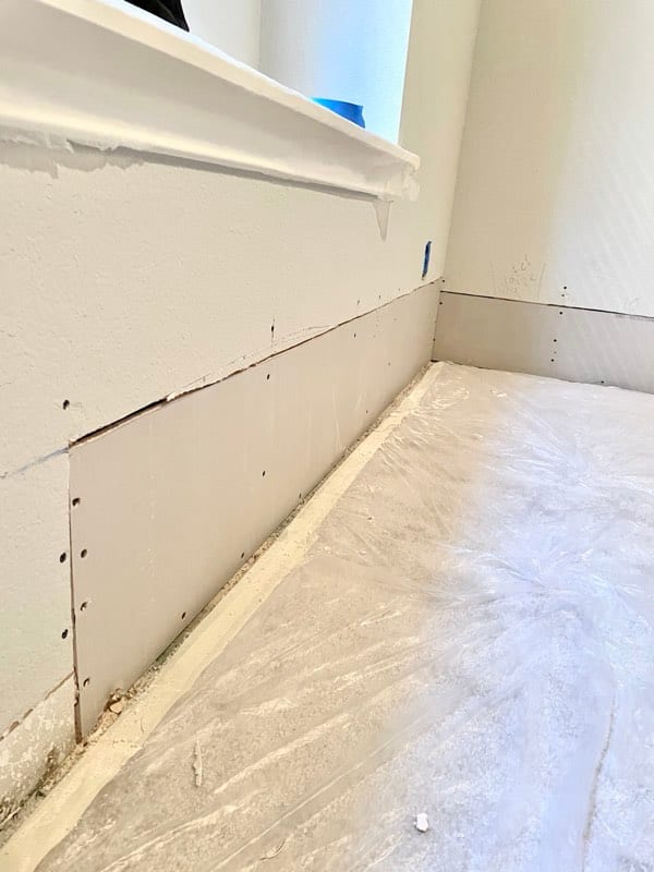 New drywall board fitted and screwed into place along the wall